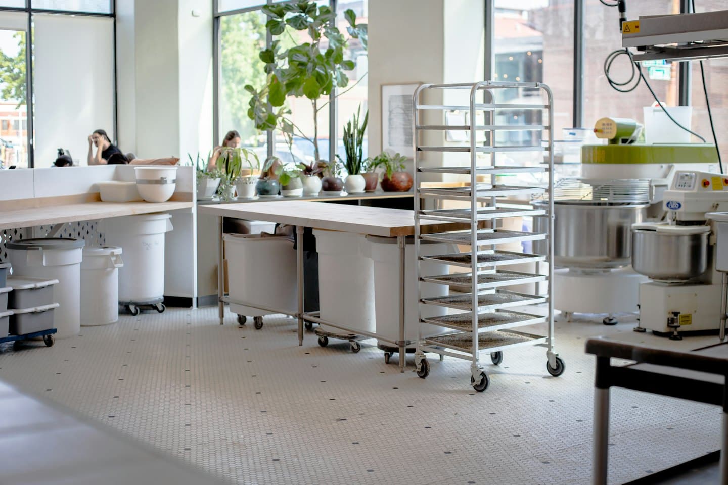 Commercial kitchen with stainless steel mixers and racks.