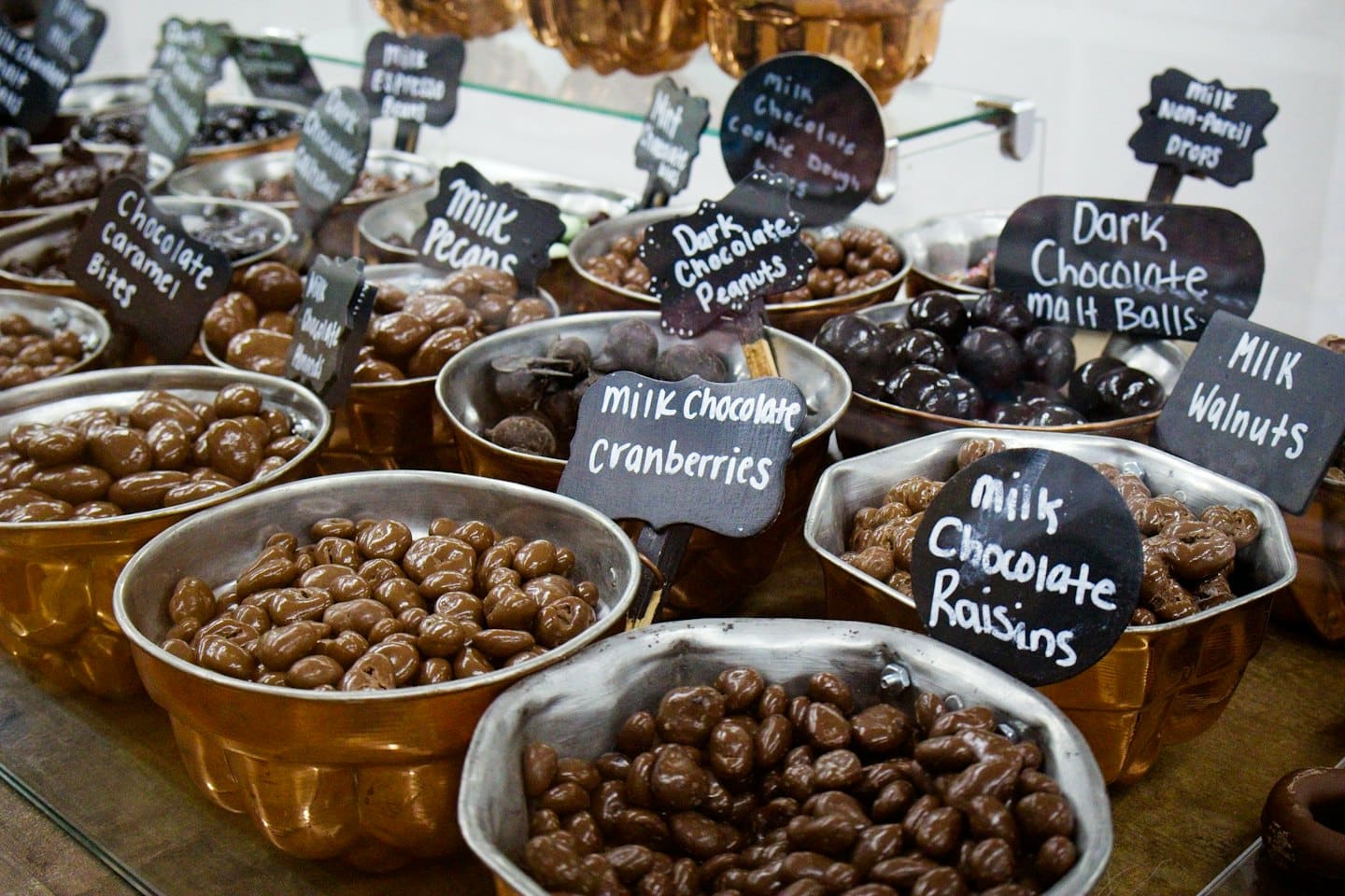 Bowls of assorted chocolate candies labeled with small chalkboard signs.